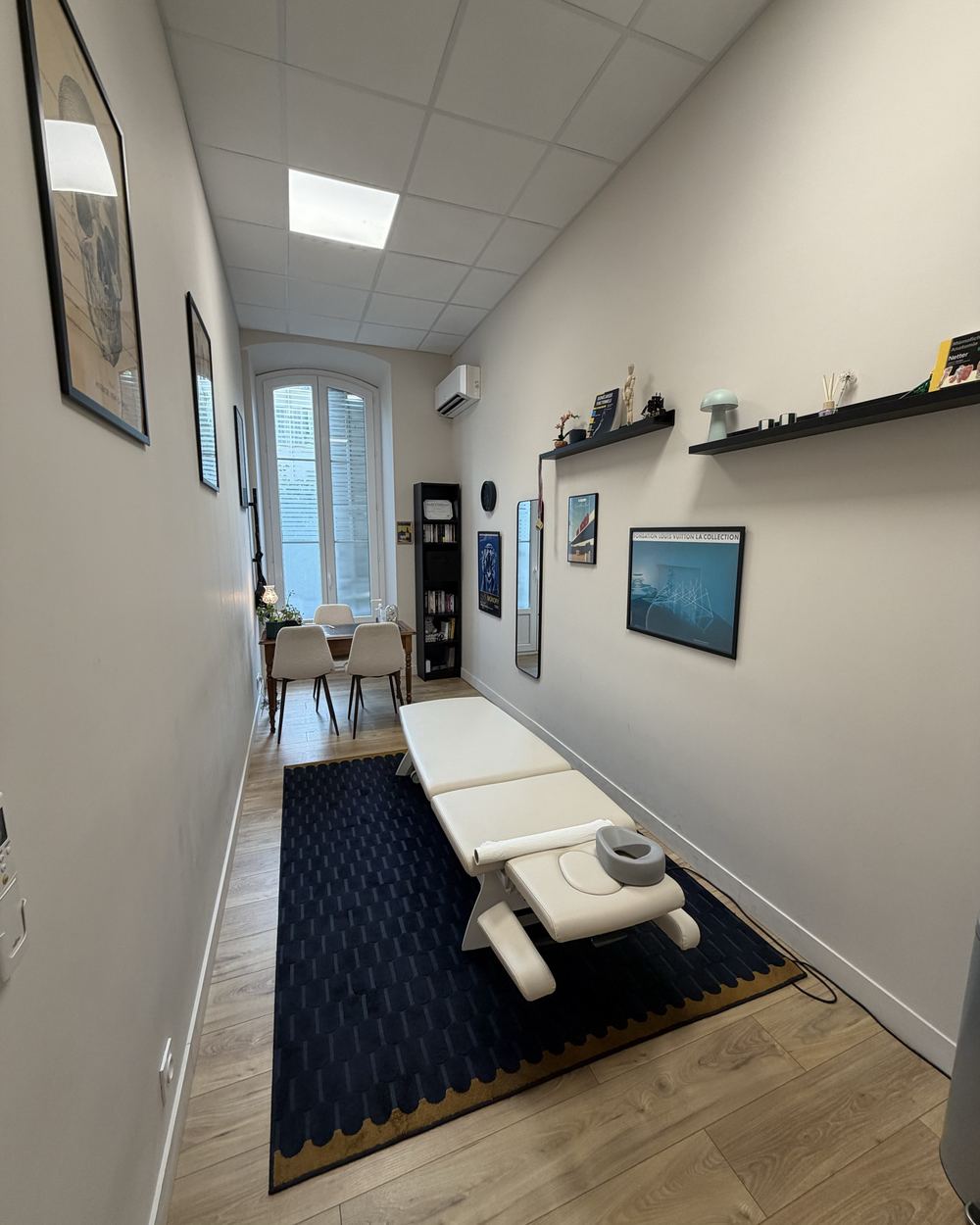 La salle de soin : table de traitement blanche sur un tapis bleu marine